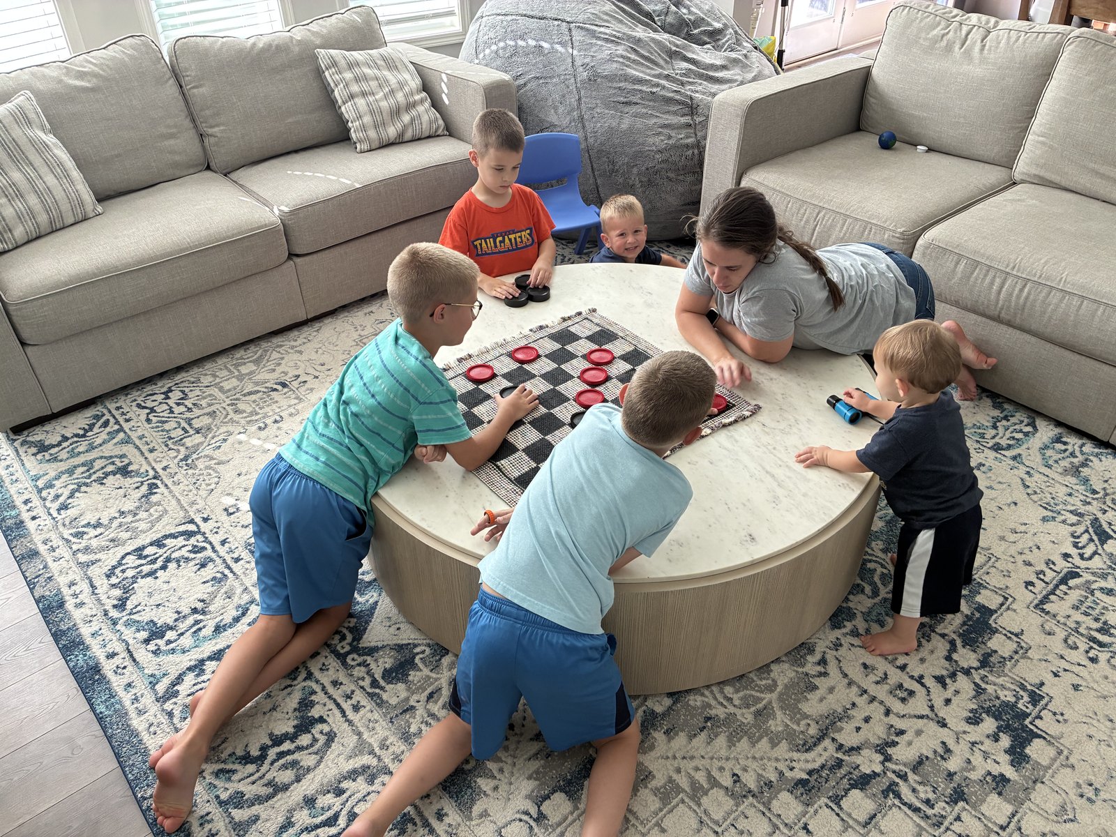 Mom and the five boys crowded around the coffee table playing a game of checkers