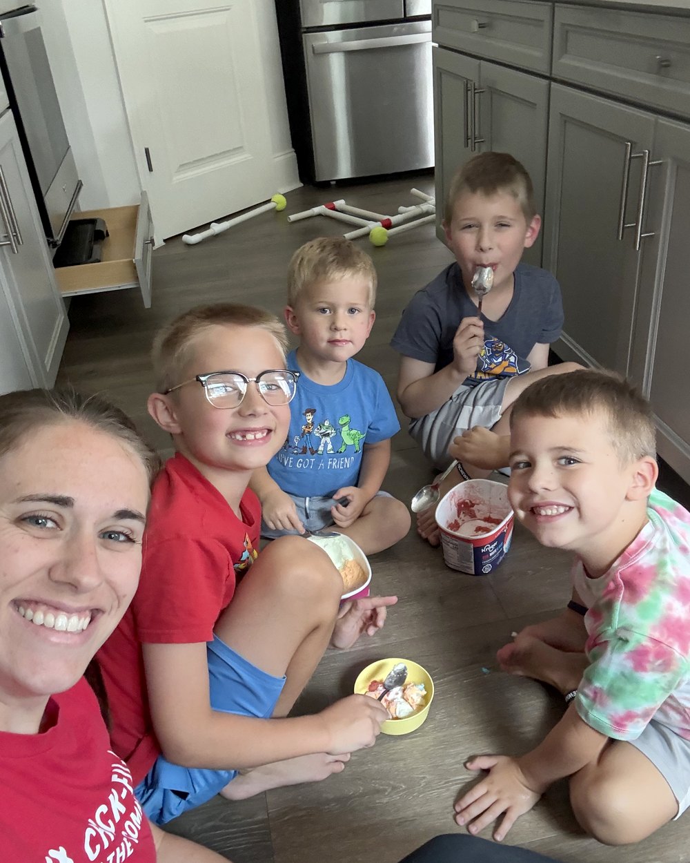 Mom and four of the boys sitting on the kitchen floor with bowls of ice cream